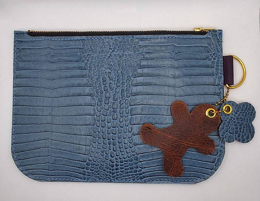 Pochette en cuir façon crocodile bleu ciel fermée par un zip doré.