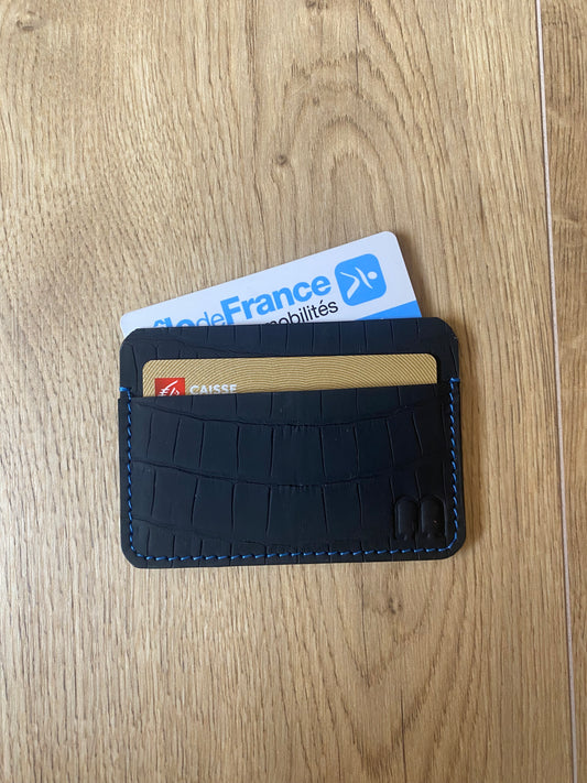 Porte carte en cuir de crocodile noir mat et surpiqure rouge sur le parquet