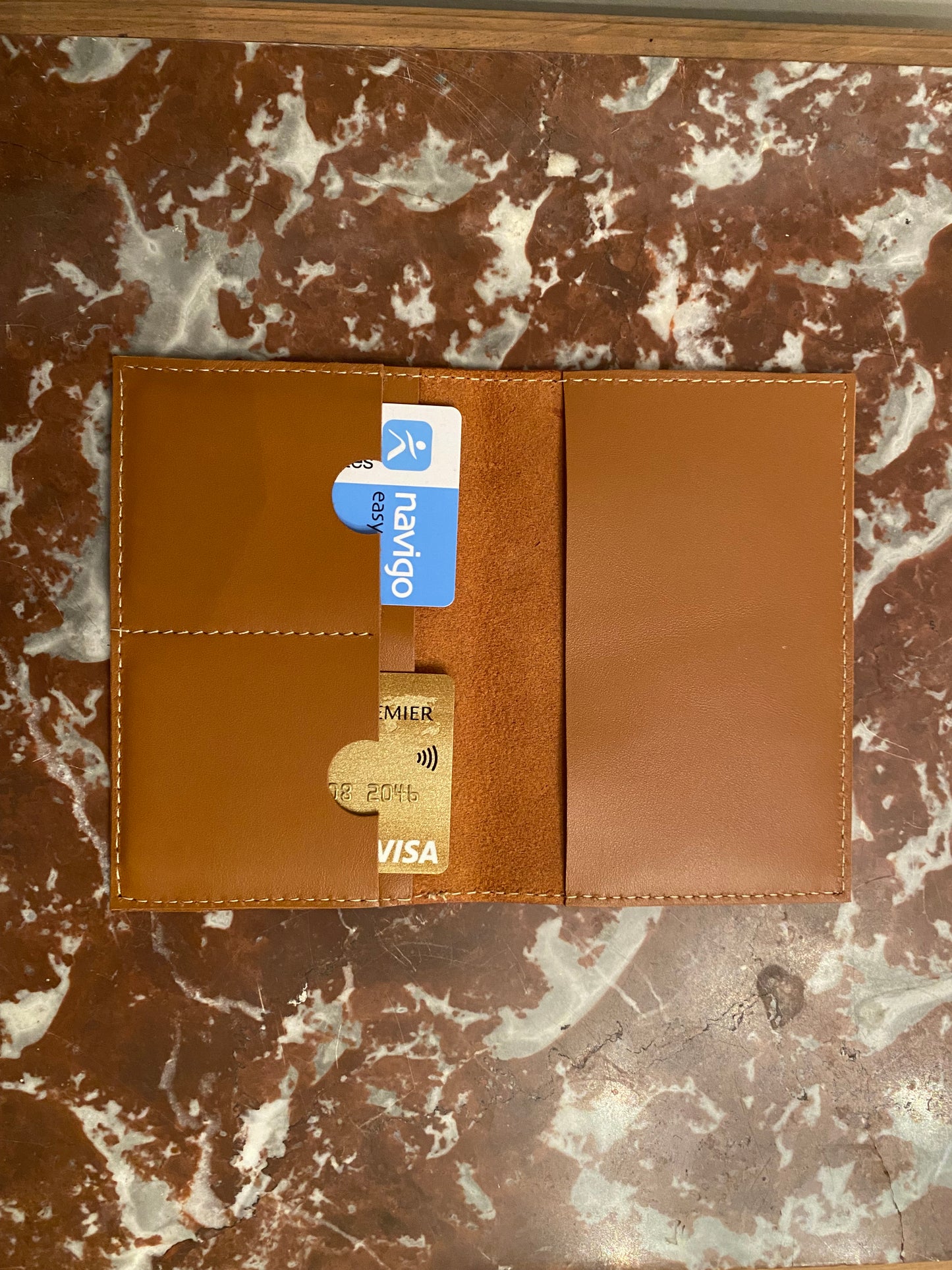 protège passeport ouvert avec des cartes dedans posé sur un plateau en marbre