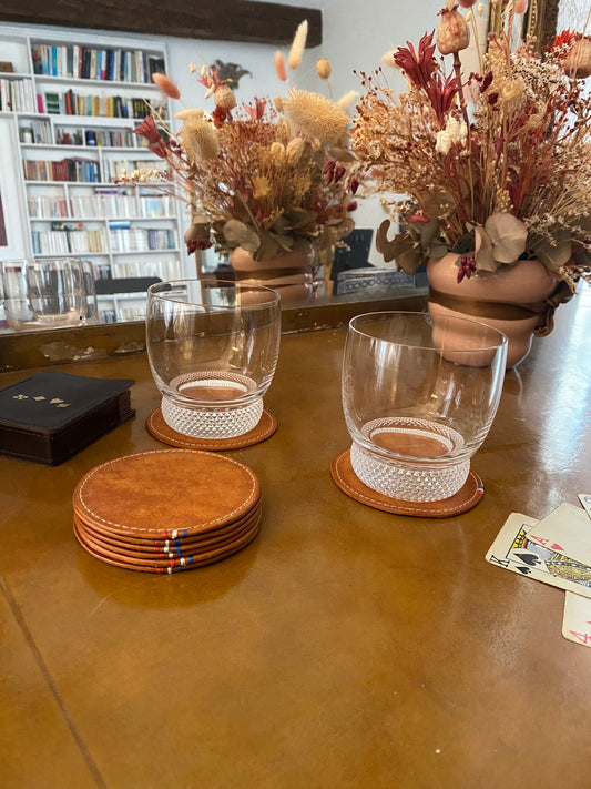 sous-verres en cuir disposés sur un bureau ancien avec un verre à whisky dessus