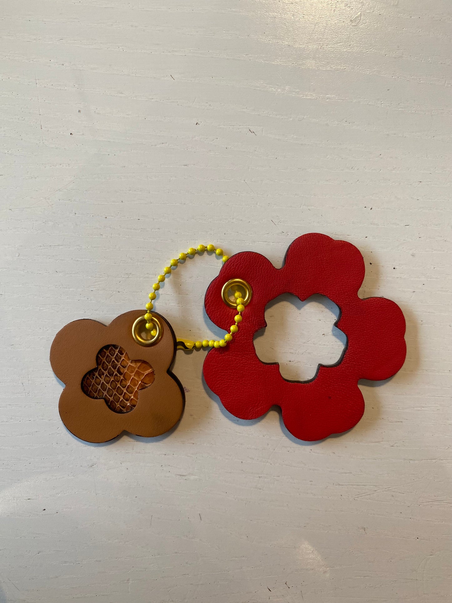Porte clef en cuir composé de deux éléments en forme de trèfle et fleur perforée en son centre.