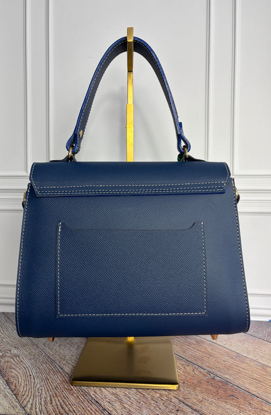 Le sac Simone en cuir bleu cobalt est présenté sur un support de sac en laiton de dos.