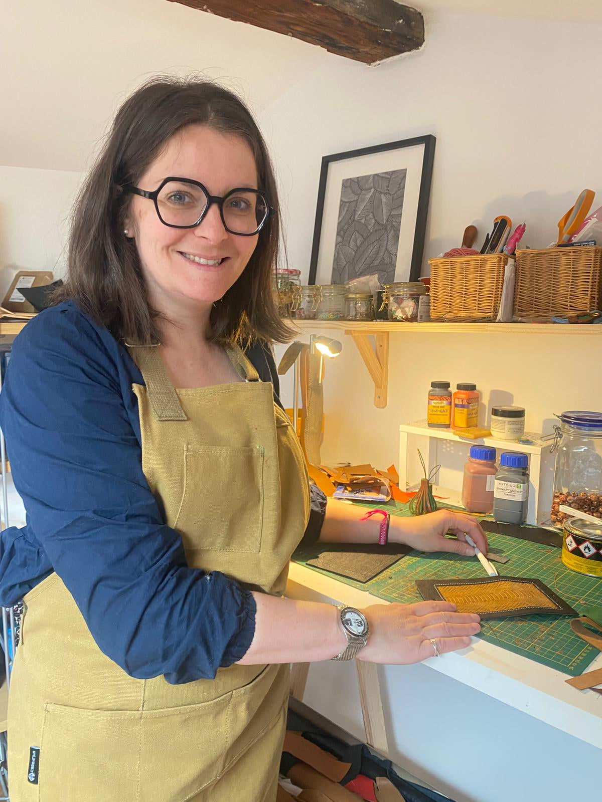 La créatrice souriante à la table de son atelier.