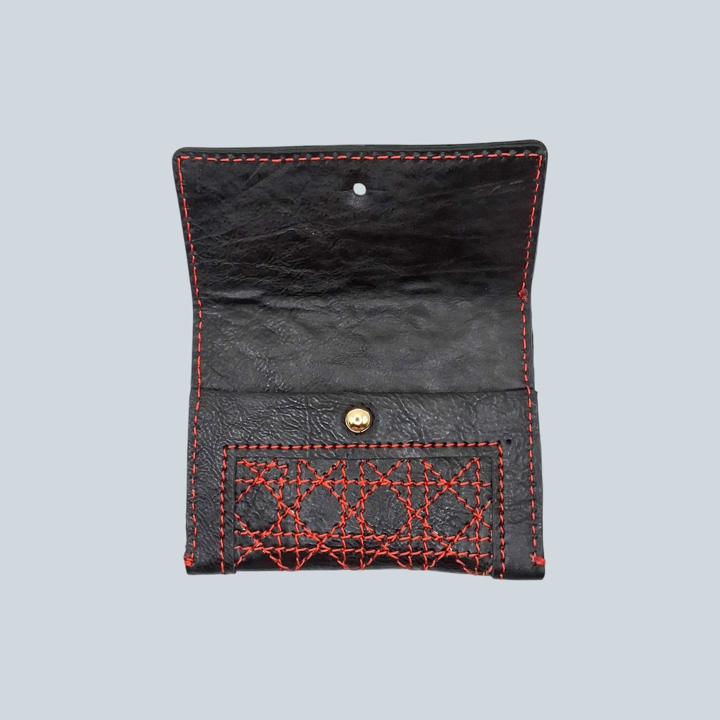 Porte carte de la collection cannage en cuir noir et surpiqures rouge vif entre ouvert sur fond blanc
