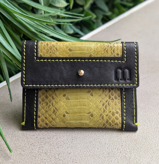 Porte cartes noir et vert jaune serpent d'eau disposé sur une table grise avec un fond végétal.