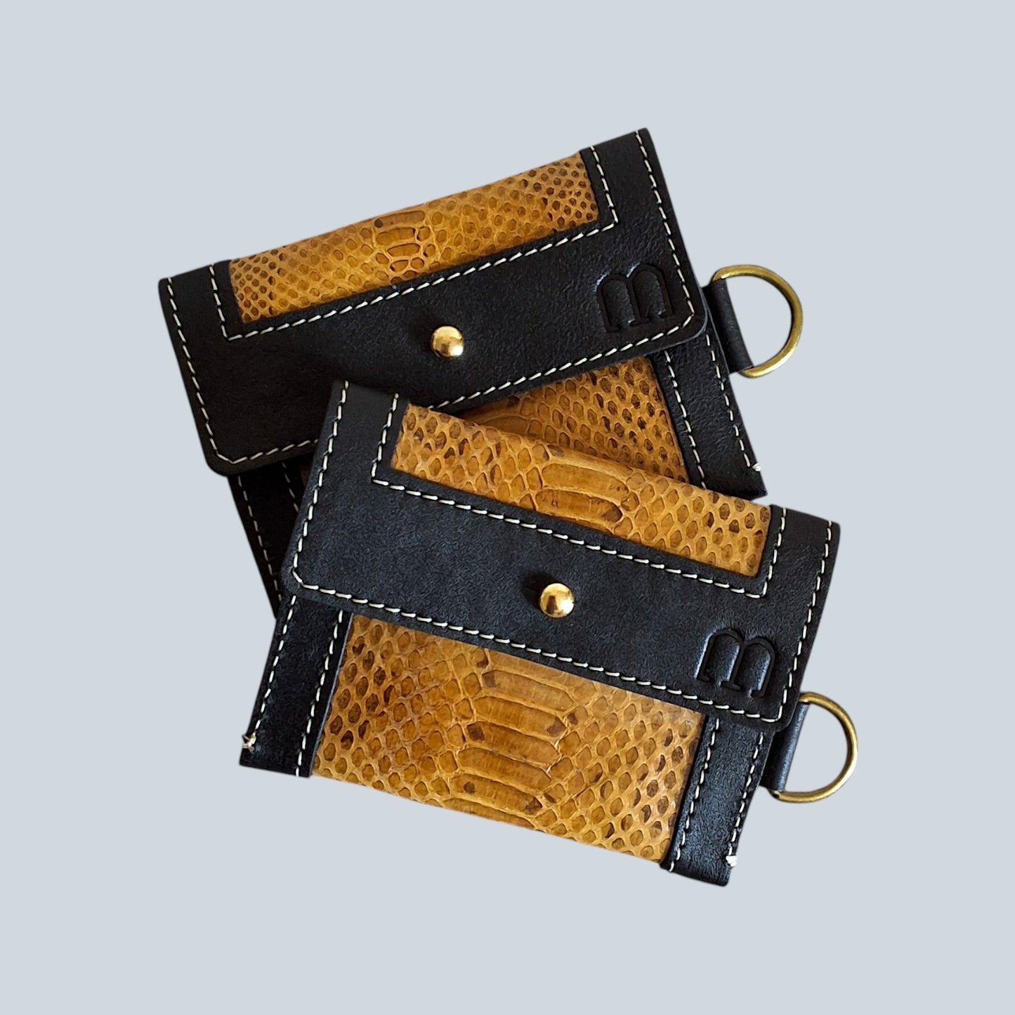 2 portes cartes noir et serpent d'eau marron clair et surpiqûres blanches, mousqueton doré à droite, pliés l'un sur l'autre.