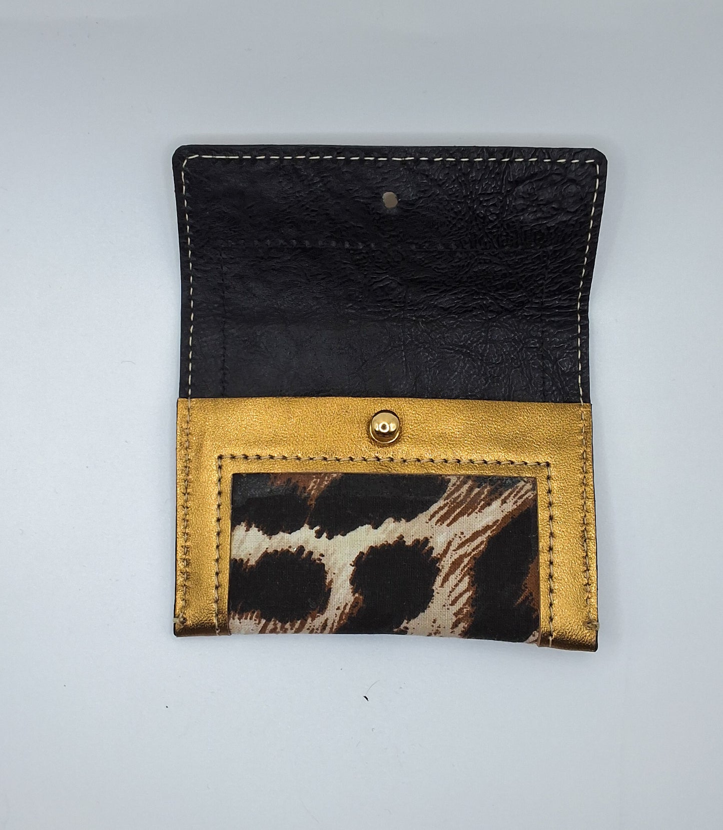 Portes cartes déplié noir, doré et motif léopard avec un bouton doré au milieu.