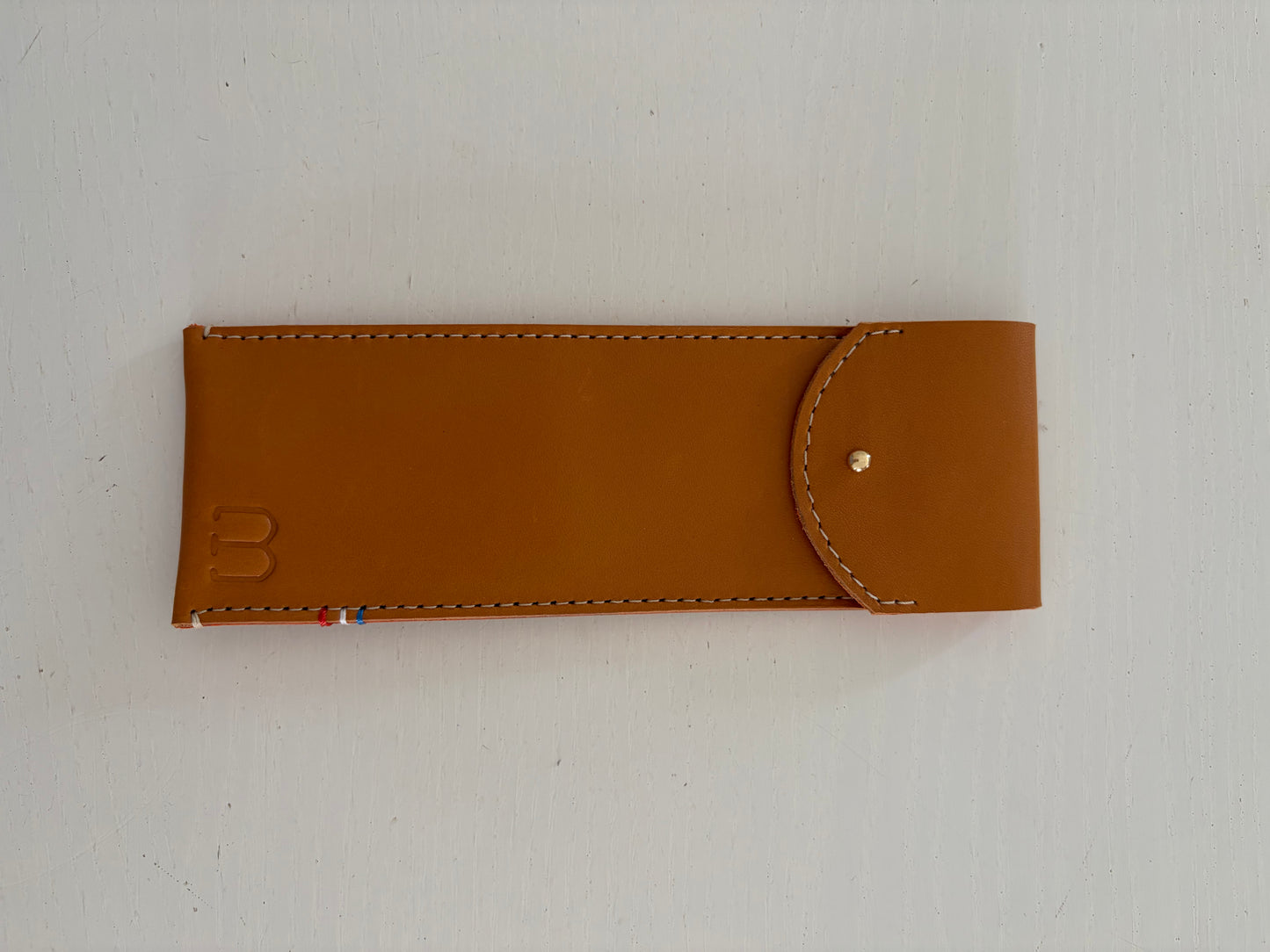 un étui en cuir marron est présenté fermé.