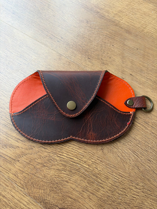 étui à lunette marron et orange sur un sol parquet bois