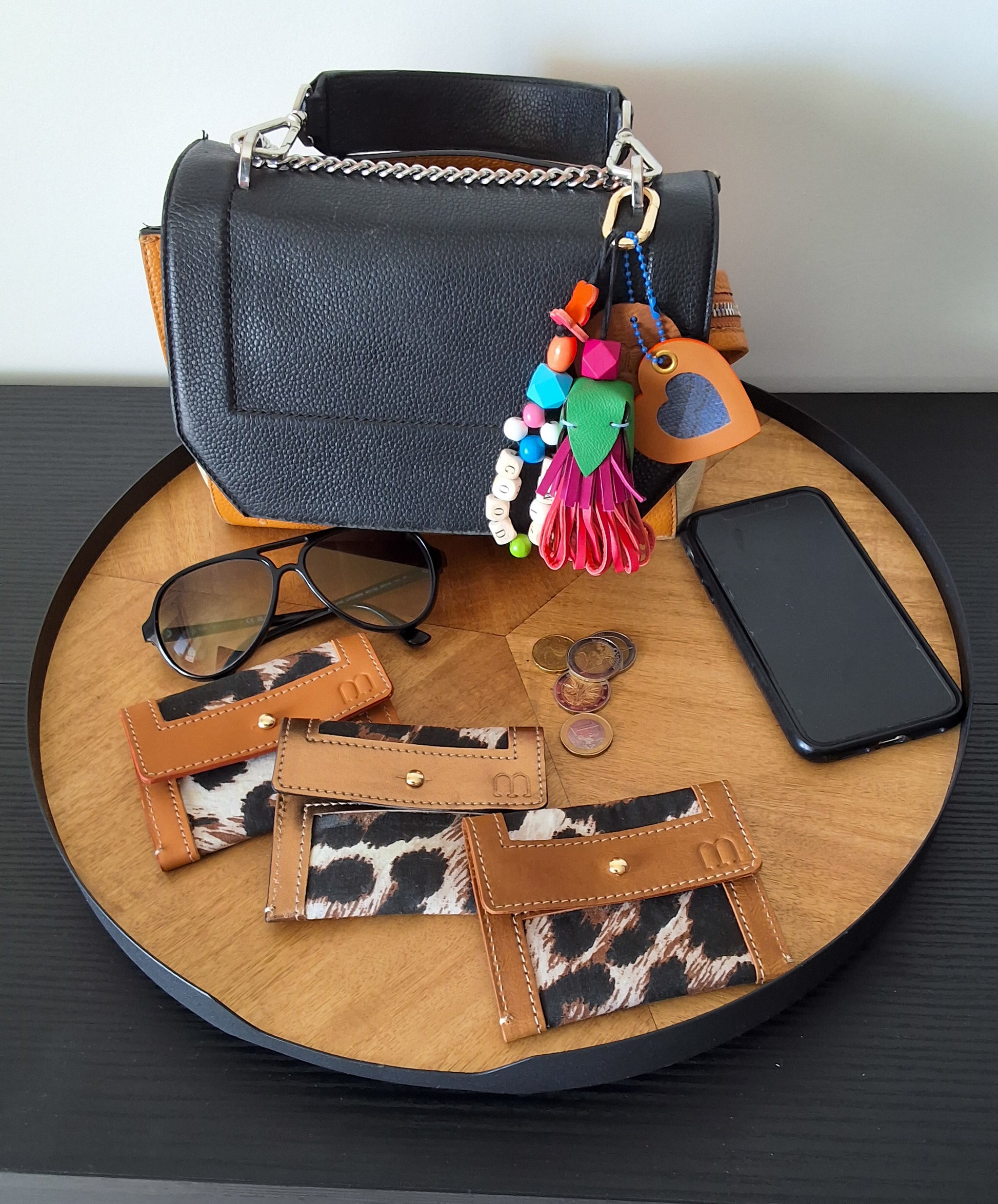 Sur un plateau en bois tournant 3 porte carteen cuir camel et fond en tissus leopard 