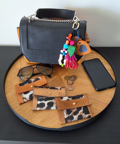Sur un plateau en bois tournant 3 porte carteen cuir camel et fond en tissus leopard 