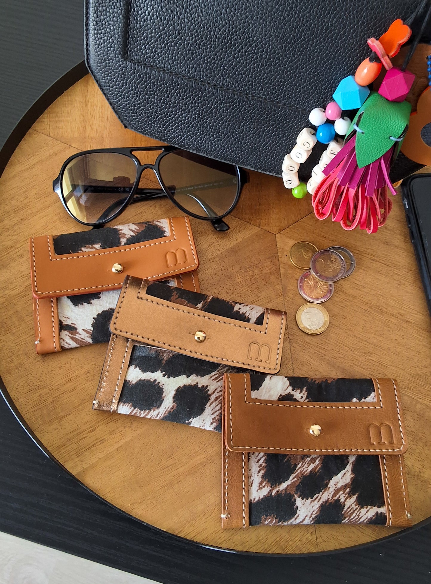 Sur un plateau tournant en bois 3 porte carte en cuir camel et fonc en tissus leopard 