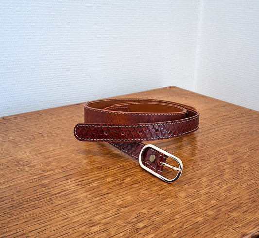 Ceinture en cuir et peau de serpent marron déposée sur un meuble en bois 
