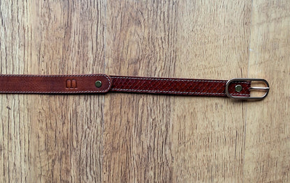 Ceinture en cuir et peau de serpent marron déposée sur un meuble en bois 