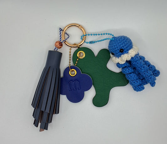 Bijoux de sac en cuir aux tons vert et bleu sur fond blanc 