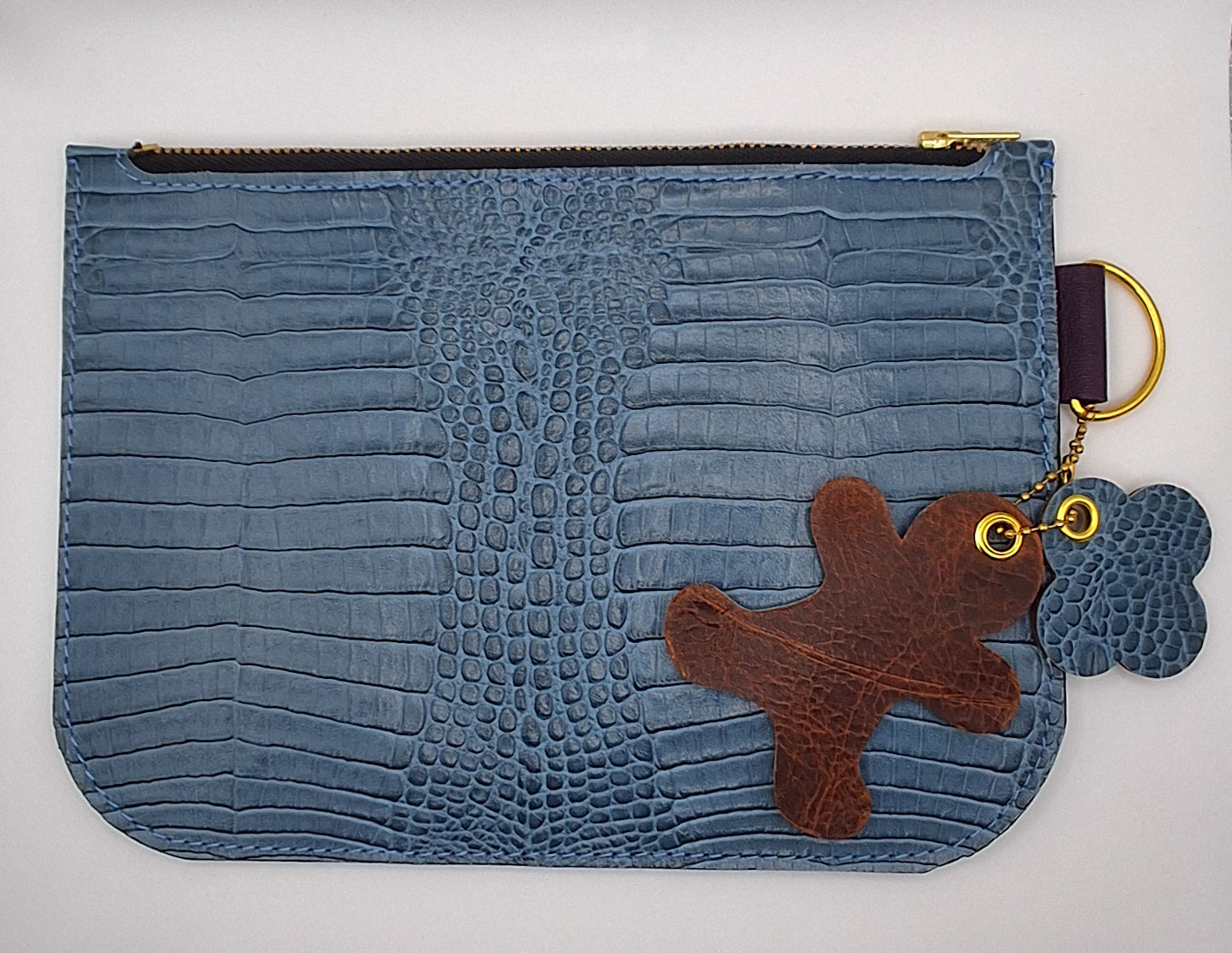 Pochette en cuir façon crocodile bleu ciel fermée par un zip doré. 