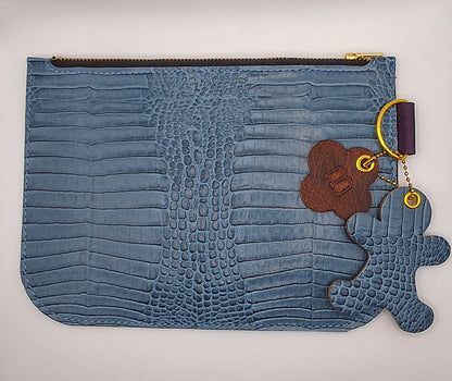 Pochette en cuir façon crocodile bleu ciel fermée par un zip doré. 