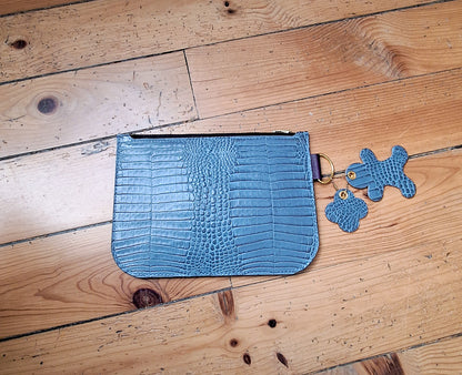 Pochette en cuir façon crocodile bleu ciel fermée par un zip doré. 