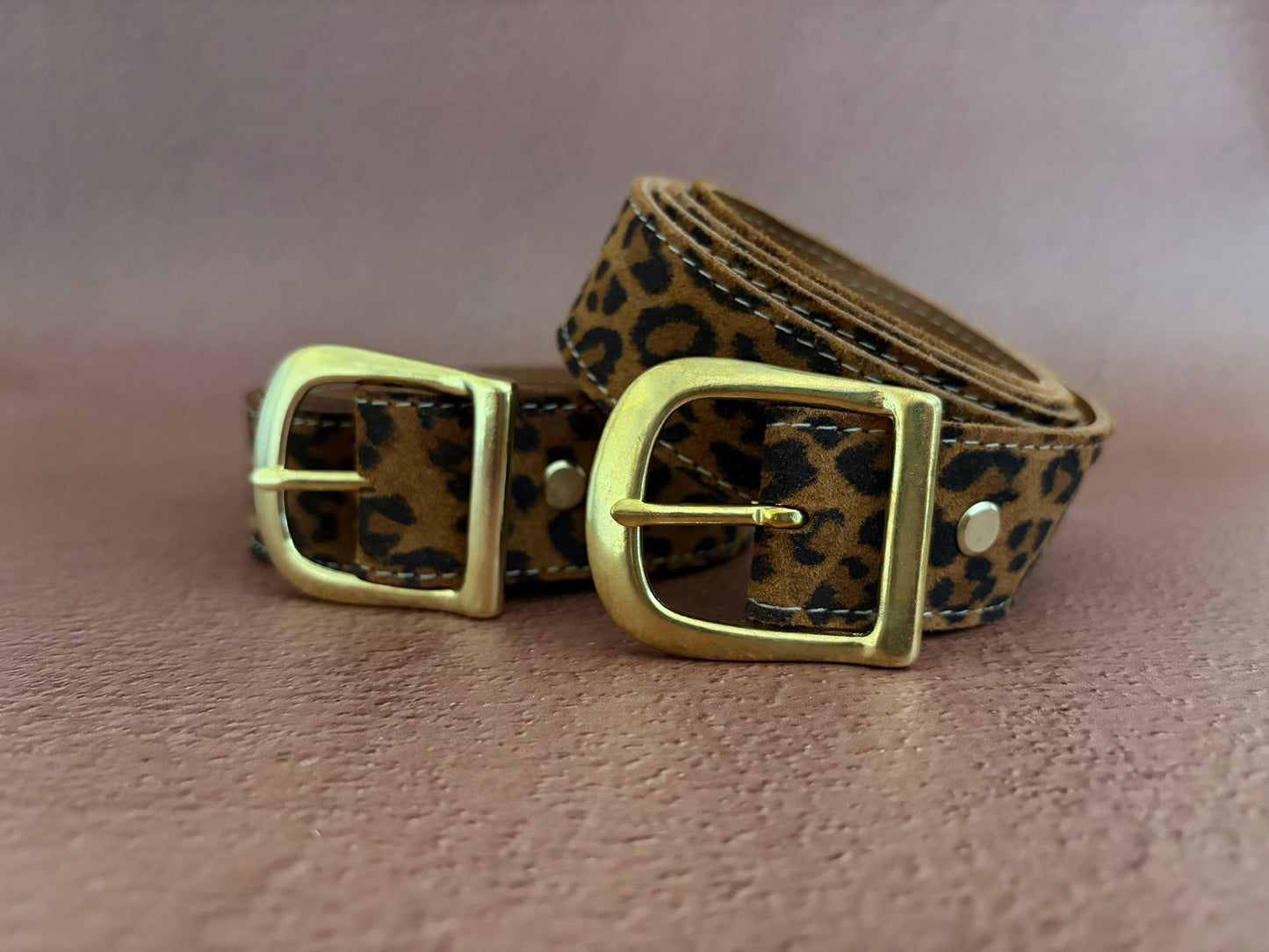 les 2 ceintures en cuir fantaisie léopard sont présentées enroulées les boucles en laiton en avant. 