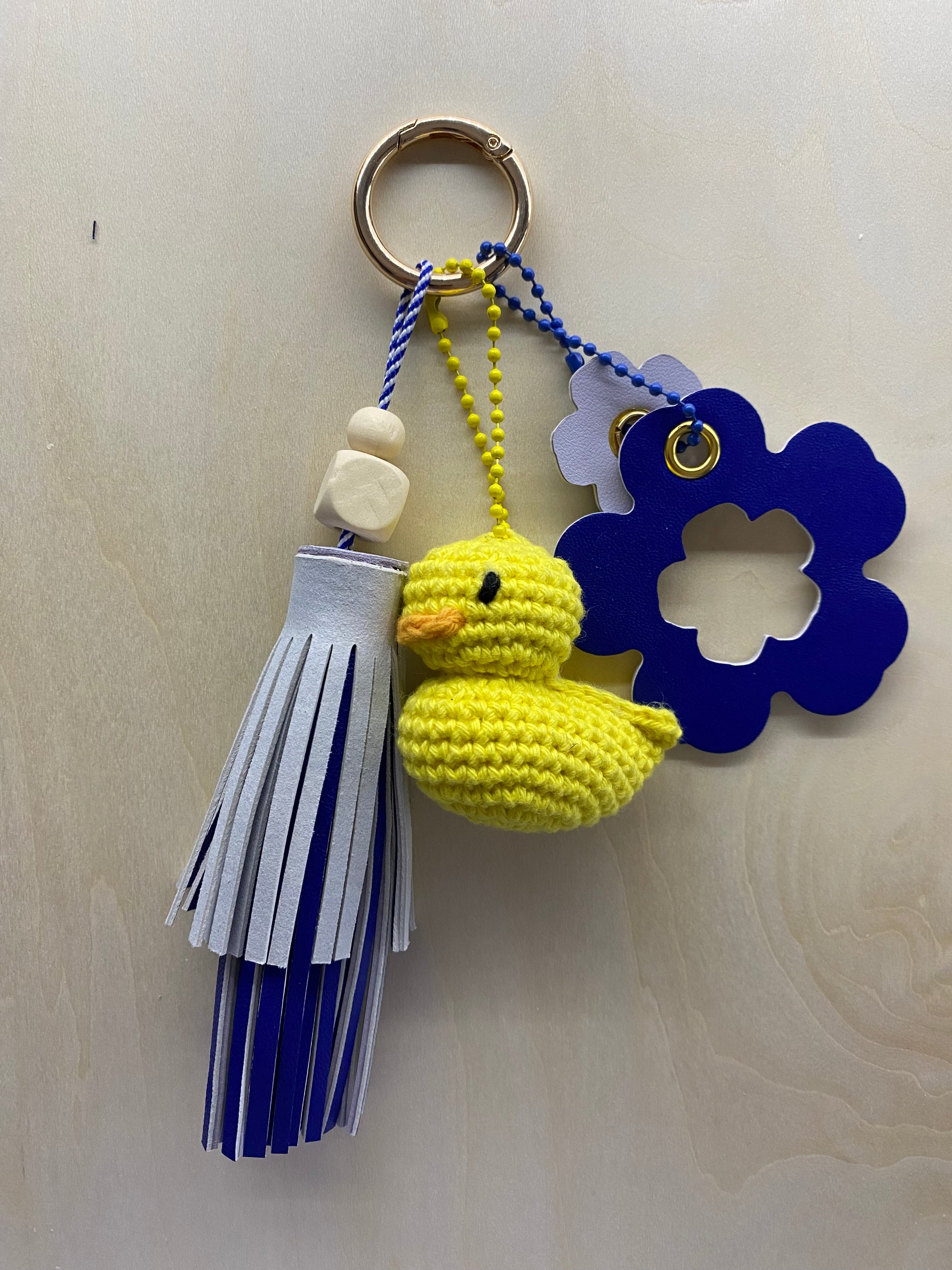 Bijoux de sac 4 breloques dans les tons mauve et parme sur un fond en bois.