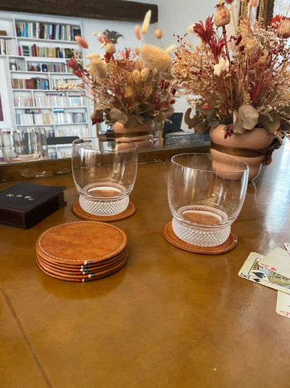 sous-verres en cuir disposés sur un bureau ancien avec un verre à whisky dessus
