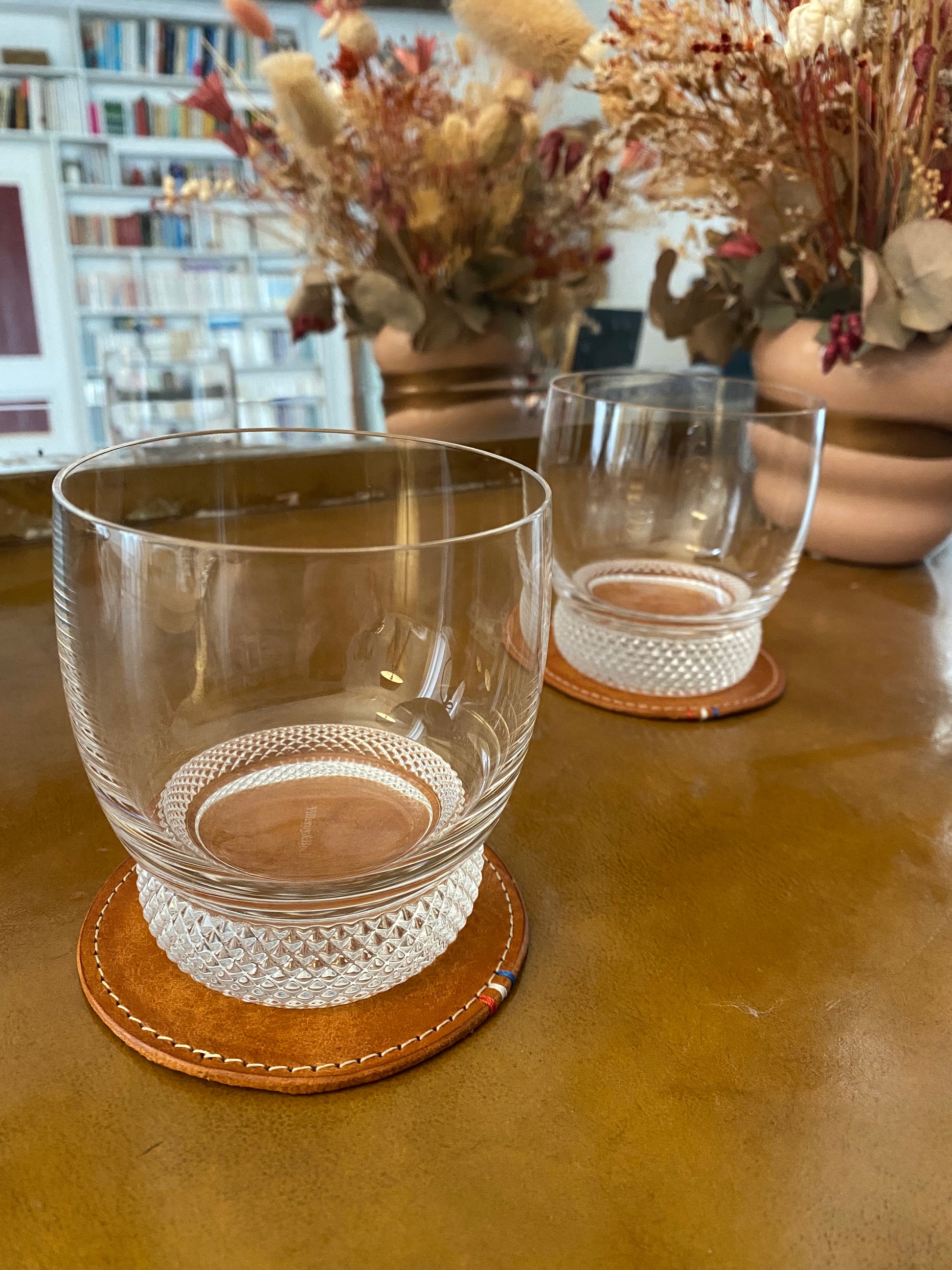 sous-verres en cuir disposés sur un bureau ancien avec un verre à whisky dessus