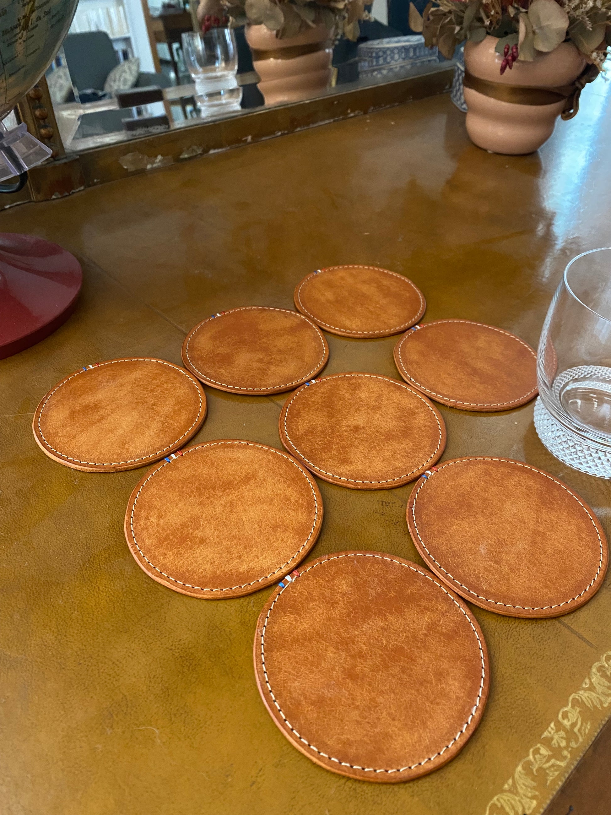 sous-verres en cuir disposés sur un bureau ancien avec un verre à whisky dessus