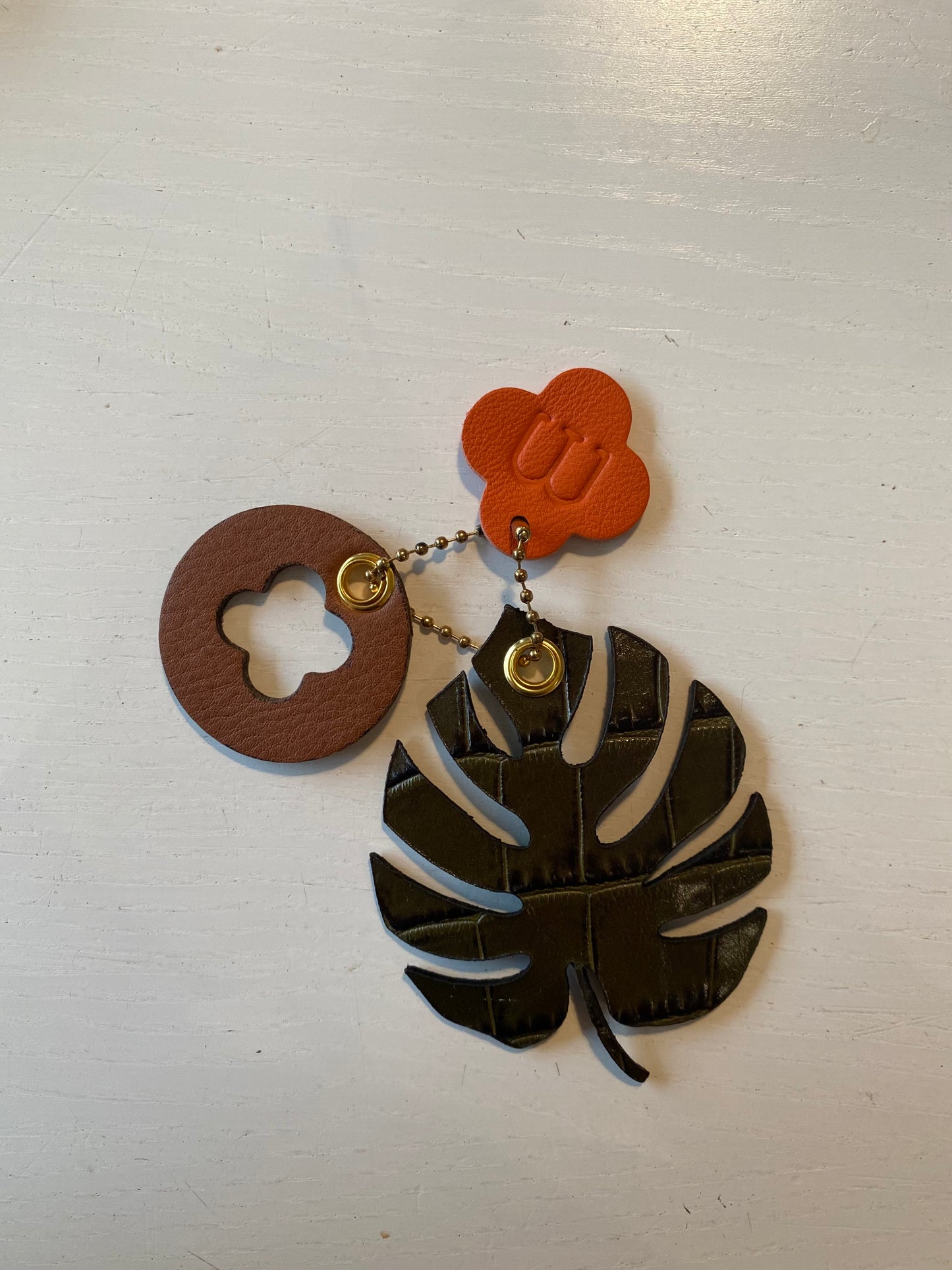 Porte clef en cuir composé de 3 éléments en forme de feuille de trèfle et de rond sur fond blanc 