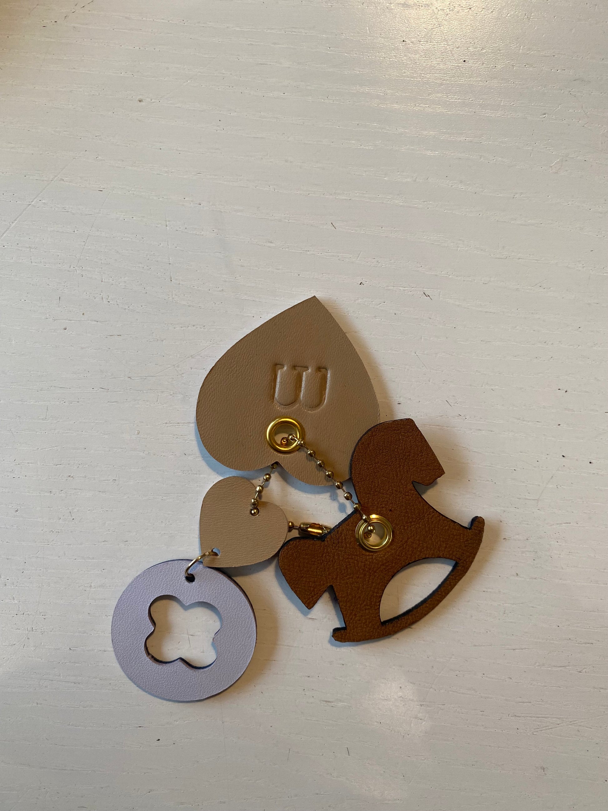 Porte clef en cuir composé de deux éléments en forme de fleur et d’un cheval à bascule 