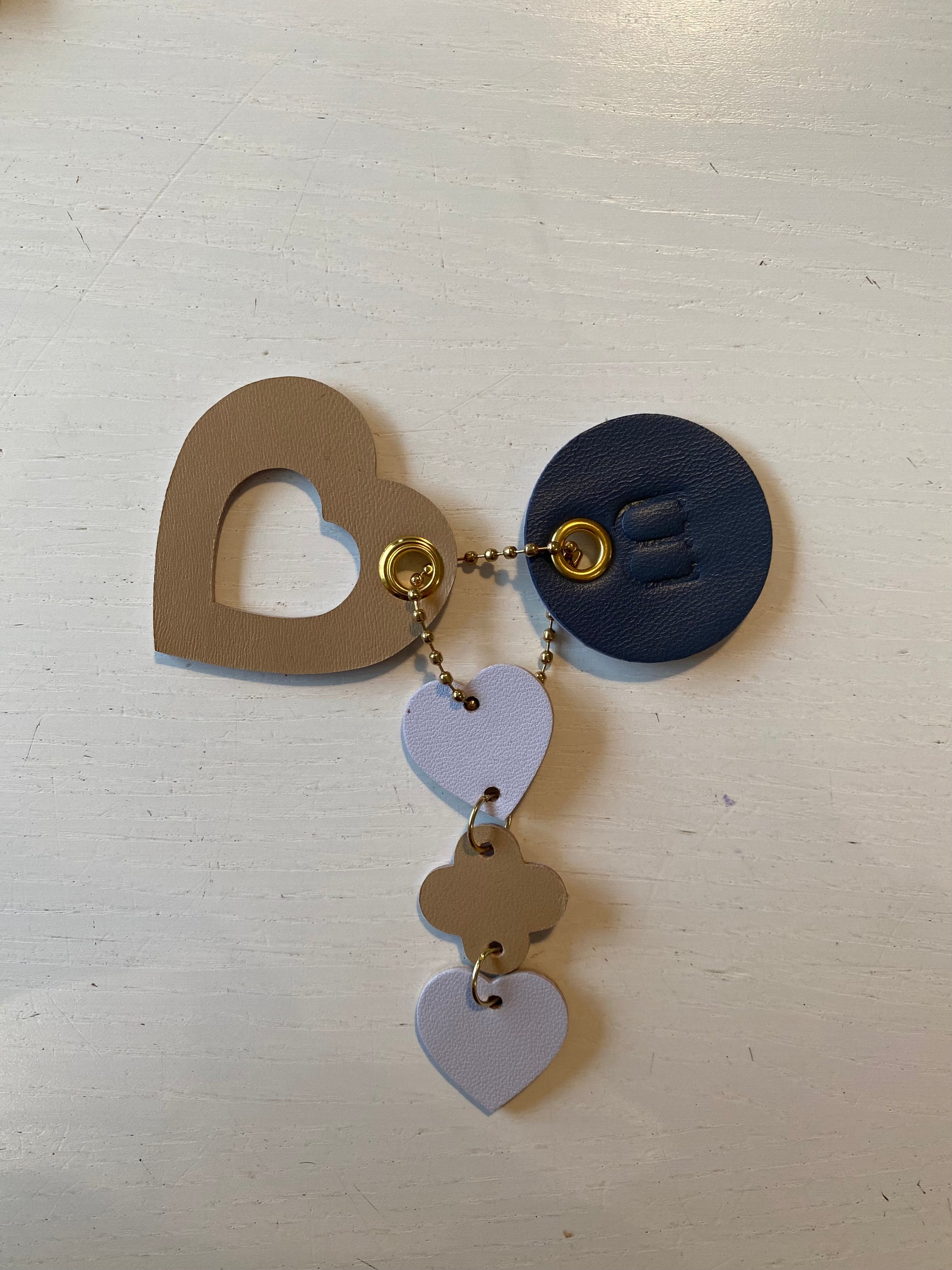 Porte clef en cuir compose de 3 éléments en forme en cœur de rond et de trèfles sur fond blanc 