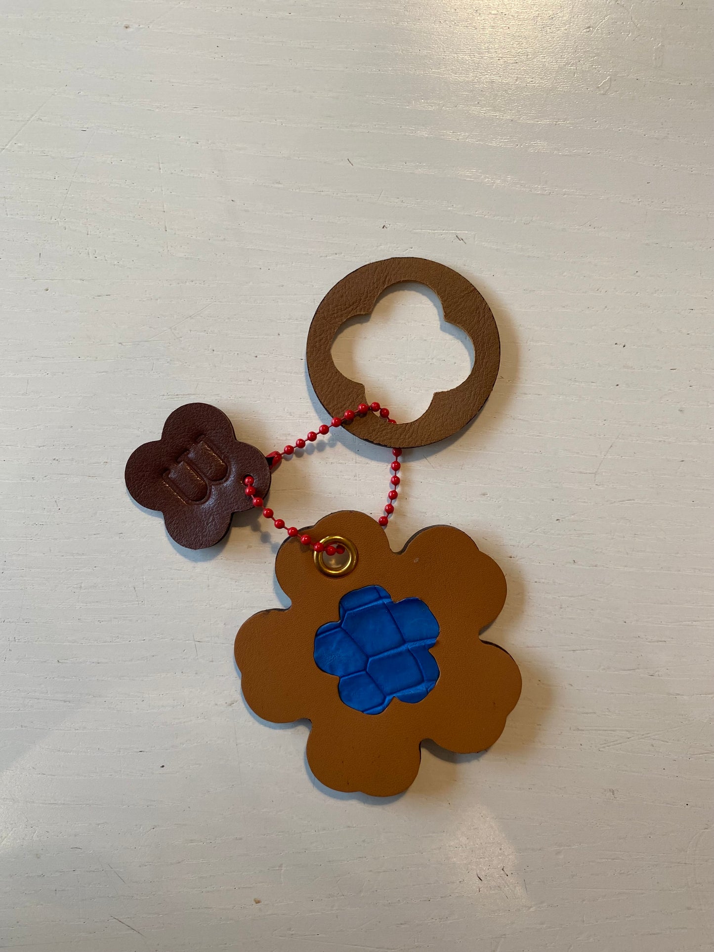 Porte clef en cuir composé de 3 éléments aux formes et couleurs variées : cercle trèfle et fleur 