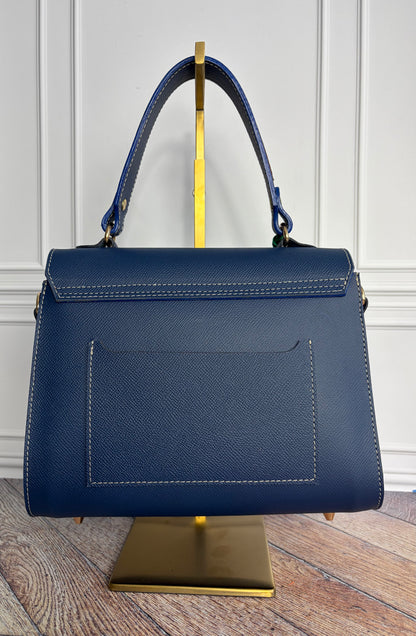 Le sac Simone en cuir bleu cobalt est présenté sur un support de sac en laiton de dos. 