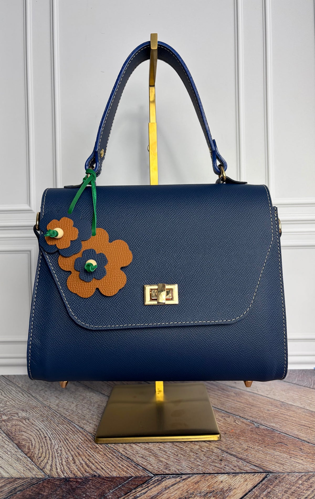 Le sac Simone en cuir bleu cobalt est présenté sur un support de sac en laiton de face. 