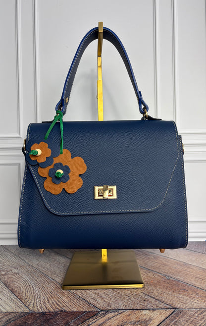 Le sac Simone en cuir bleu cobalt est présenté sur un support de sac en laiton de face. 