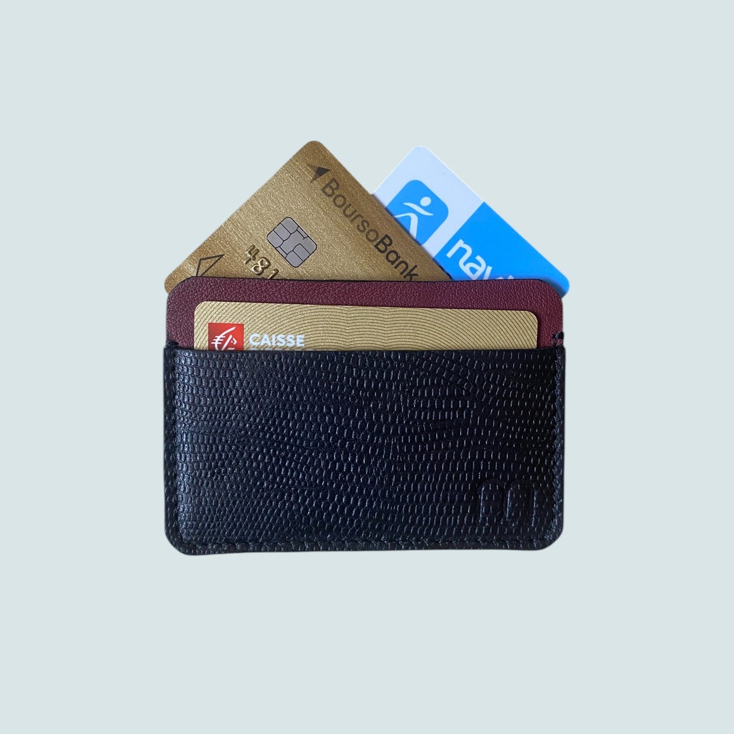 Porte carte compact en cuir noir et bordeau a deux compartiments. On voit 3 cartes banquaires qui depassent 