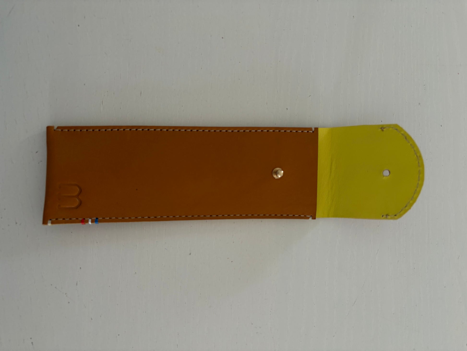 un étui en cuir marron doublé de cuir jaune est présenté ouvert. 