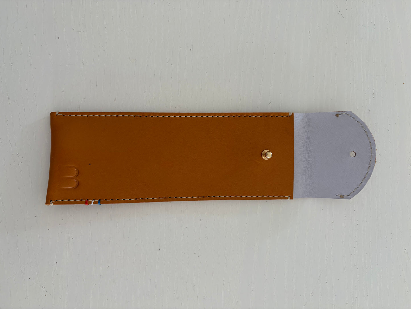 un étui en cuir marron doublé de cuir lavande est présenté ouvert. 