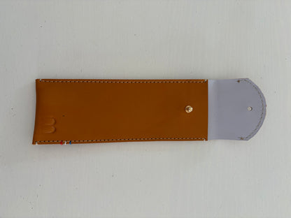 un étui en cuir marron doublé de cuir lavande est présenté ouvert. 