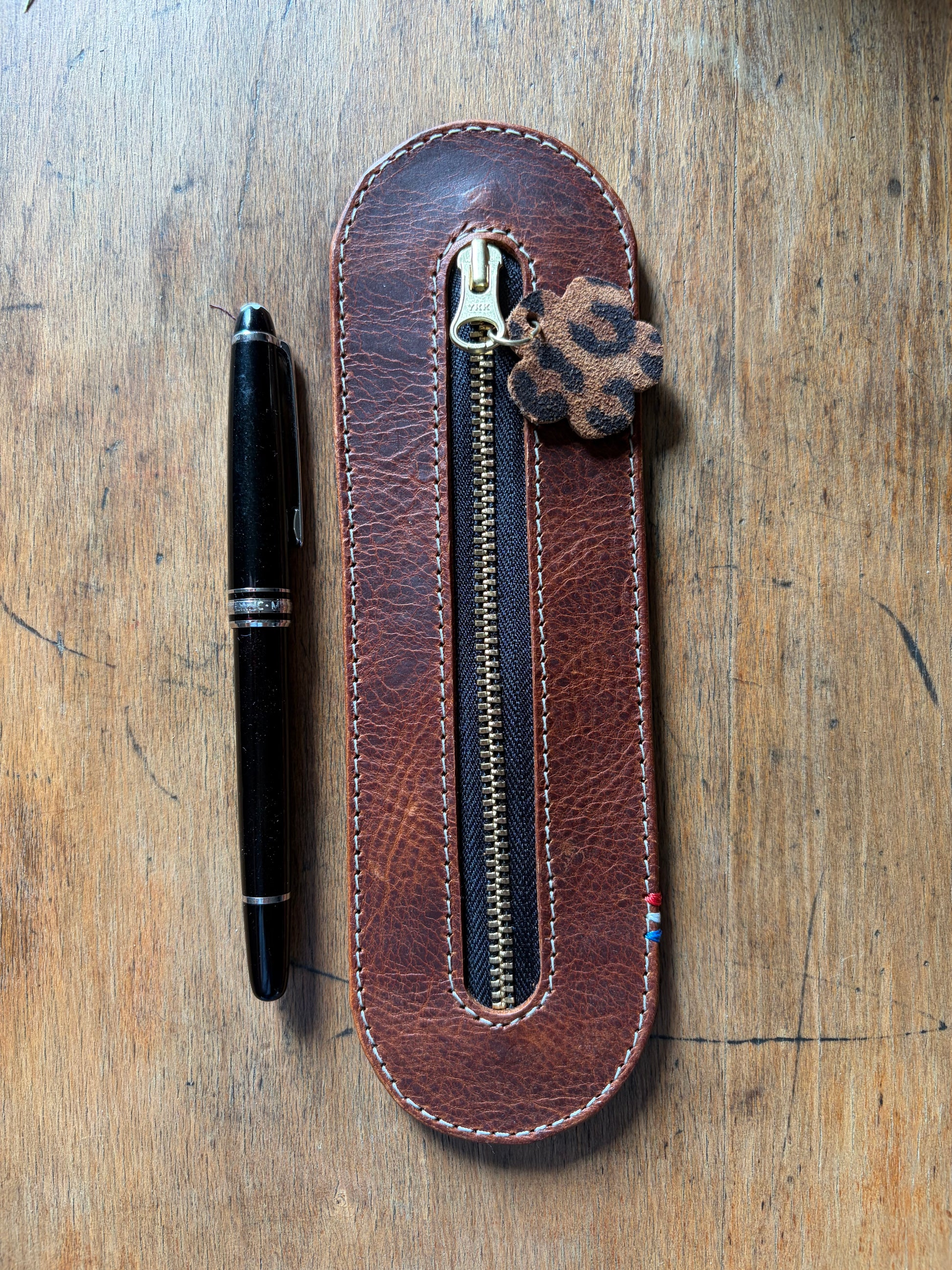 présentation d'un étui en cuir wax tannage végétal zippé avec un crayon à côté.