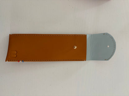 un étui en cuir marron doublé de cuir bleu ciel est présenté ouvert. 