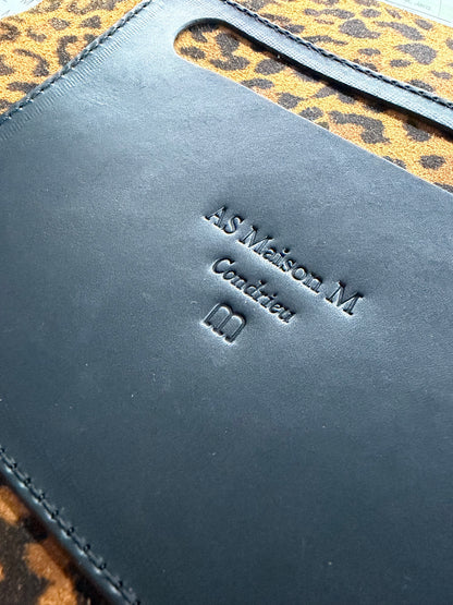 le marque de la marque AS maison M est fait sur du cuir noir par matricage à froid