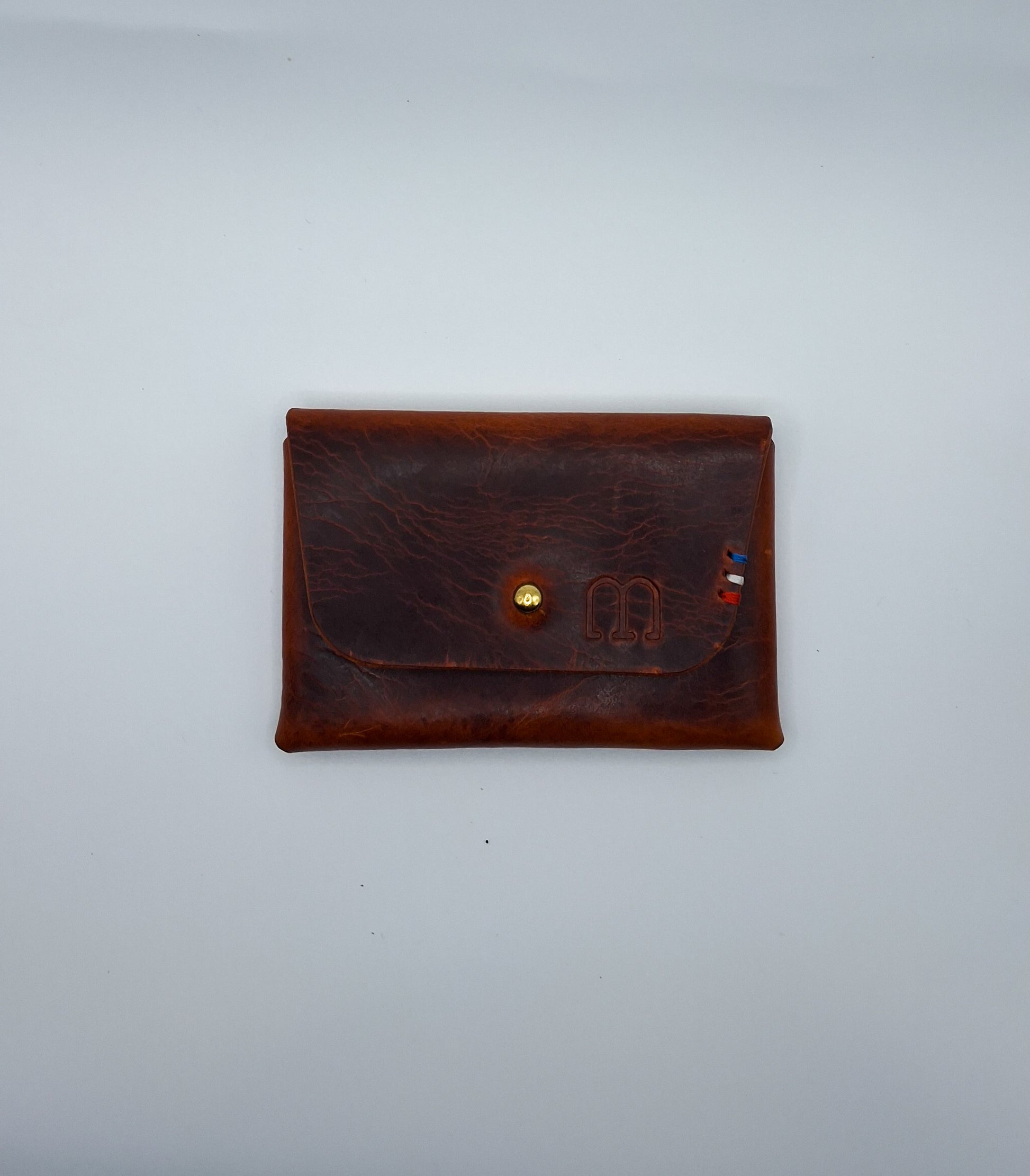 le porte carte est présenté à plat sur un fond blanc. il est en cuir wax marron