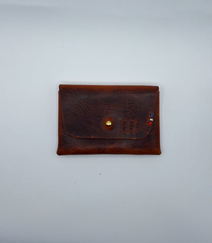 le porte carte est présenté à plat sur un fond blanc. il est en cuir wax marron