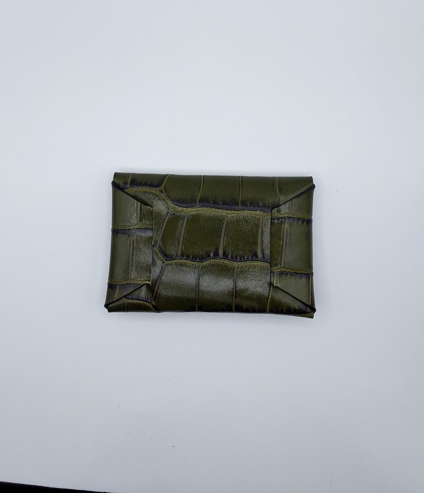 le porte carte est présenté de dos sur un fond blanc. il est en cuir façon crocodile vert foncé