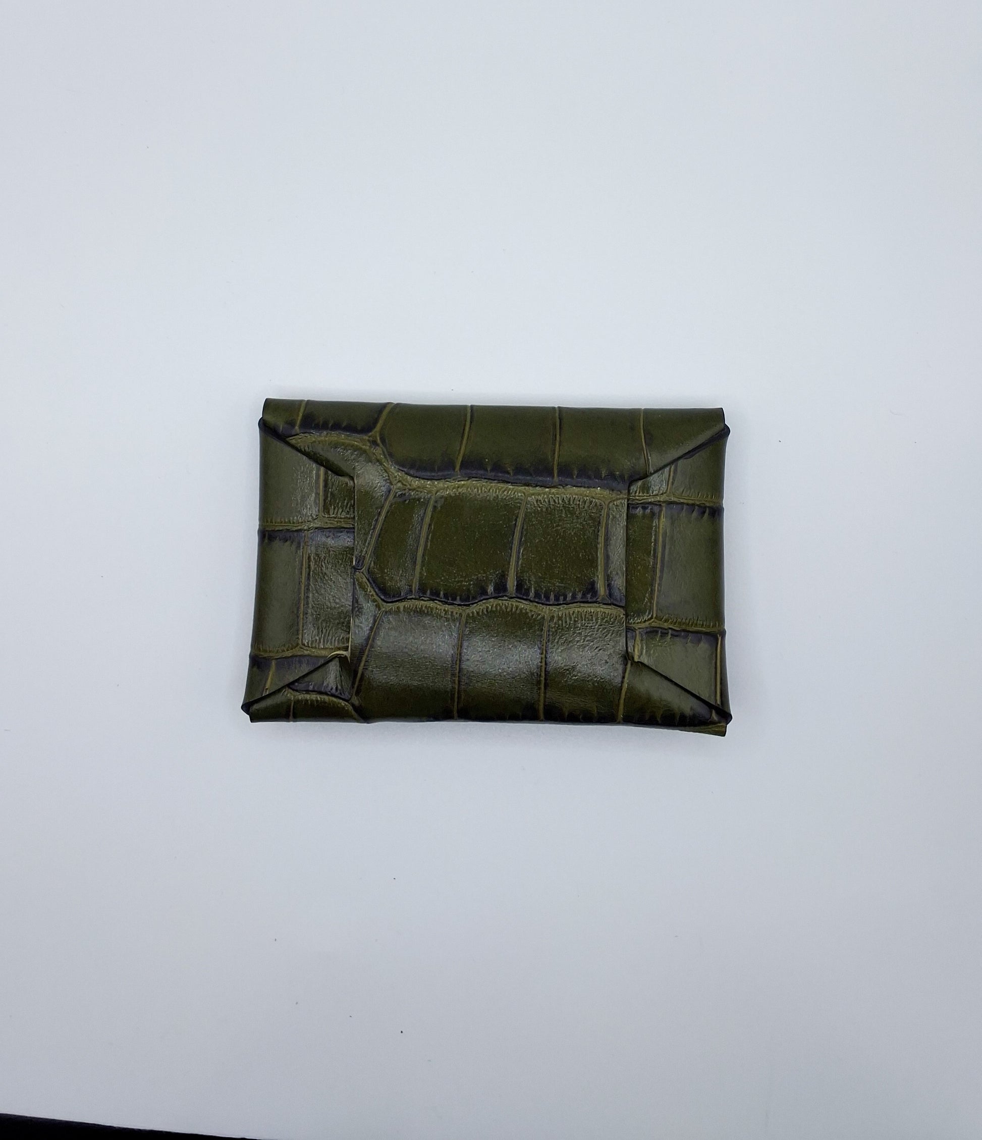le porte carte est présenté de dos sur un fond blanc. il est en cuir façon crocodile vert foncé