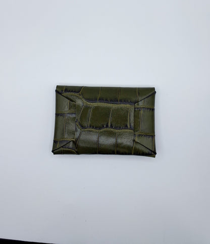 le porte carte est présenté de dos sur un fond blanc. il est en cuir façon crocodile vert foncé