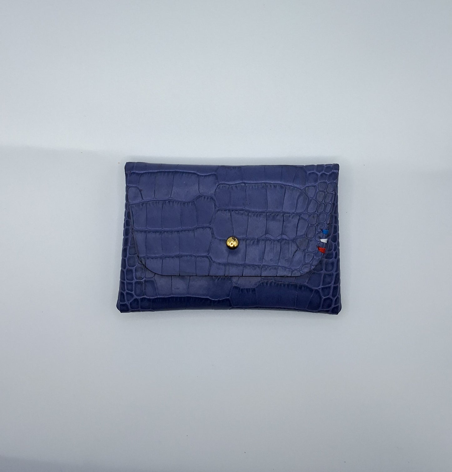 le porte carte est présenté à plat de face sur un fond blanc. il est en cuir façon crocodile violet