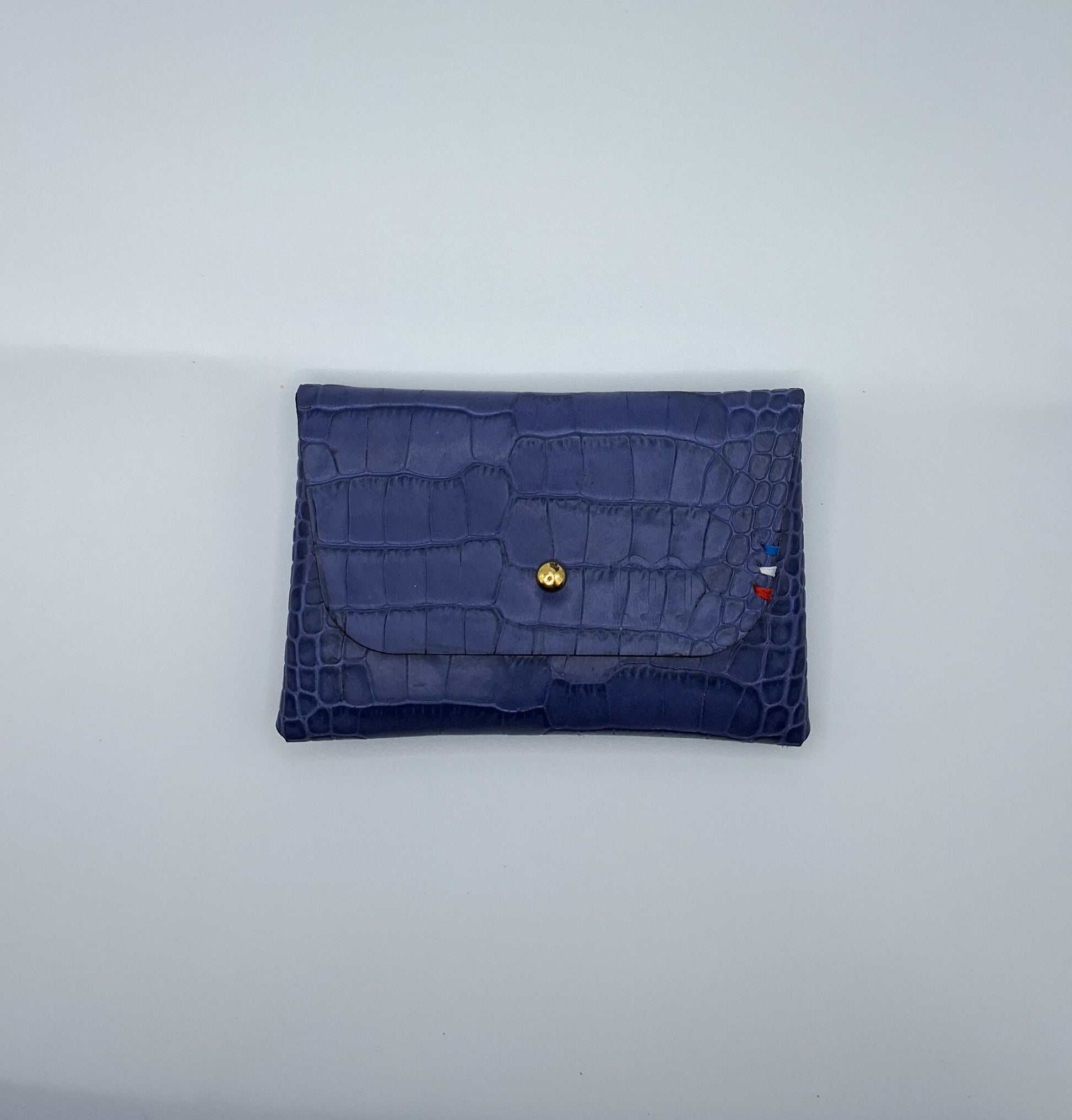 le porte carte est présenté à plat de face sur un fond blanc. il est en cuir façon crocodile violet