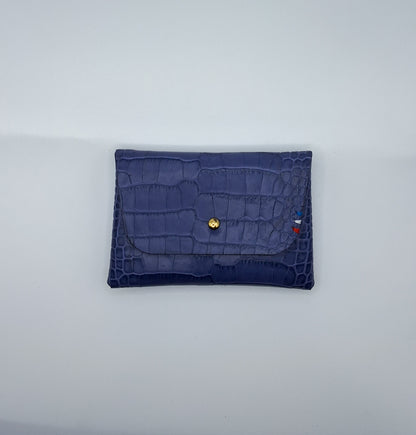 le porte carte est présenté à plat de face sur un fond blanc. il est en cuir façon crocodile violet
