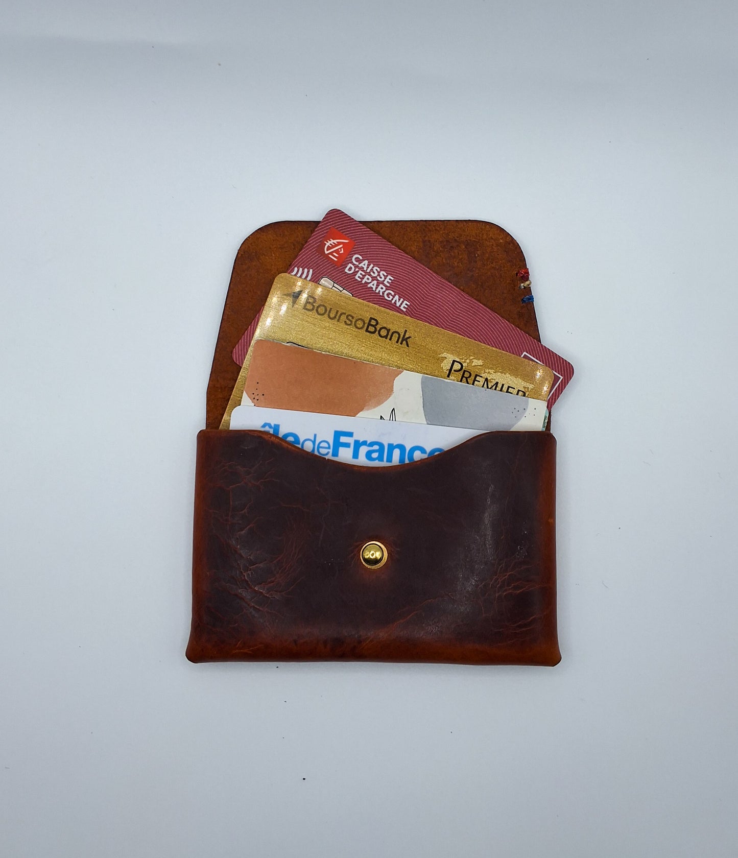 le porte carte en cuir wax marron est présenté ouvert avec des cartes qui dépassent